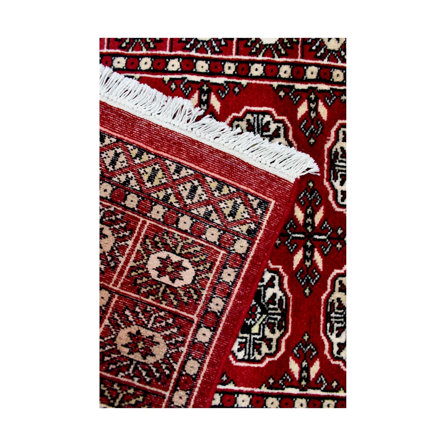 Folded corner detail of Afghan Bokhara runner rug showing the back of the rug, fringe and red front border
