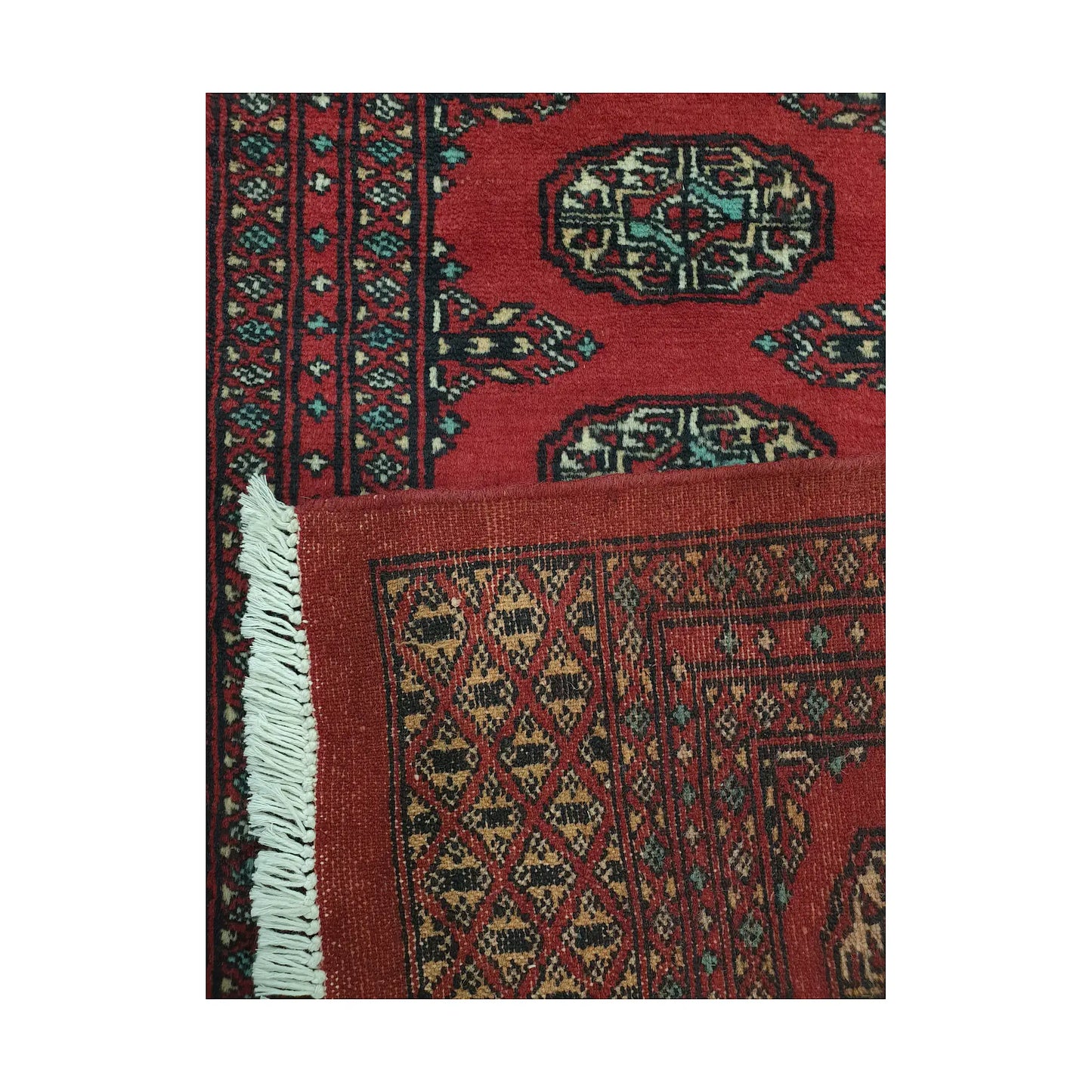 Folded corner detail of Afghan Bokhara runner rug showing the back of the rug, fringe and red front pattern