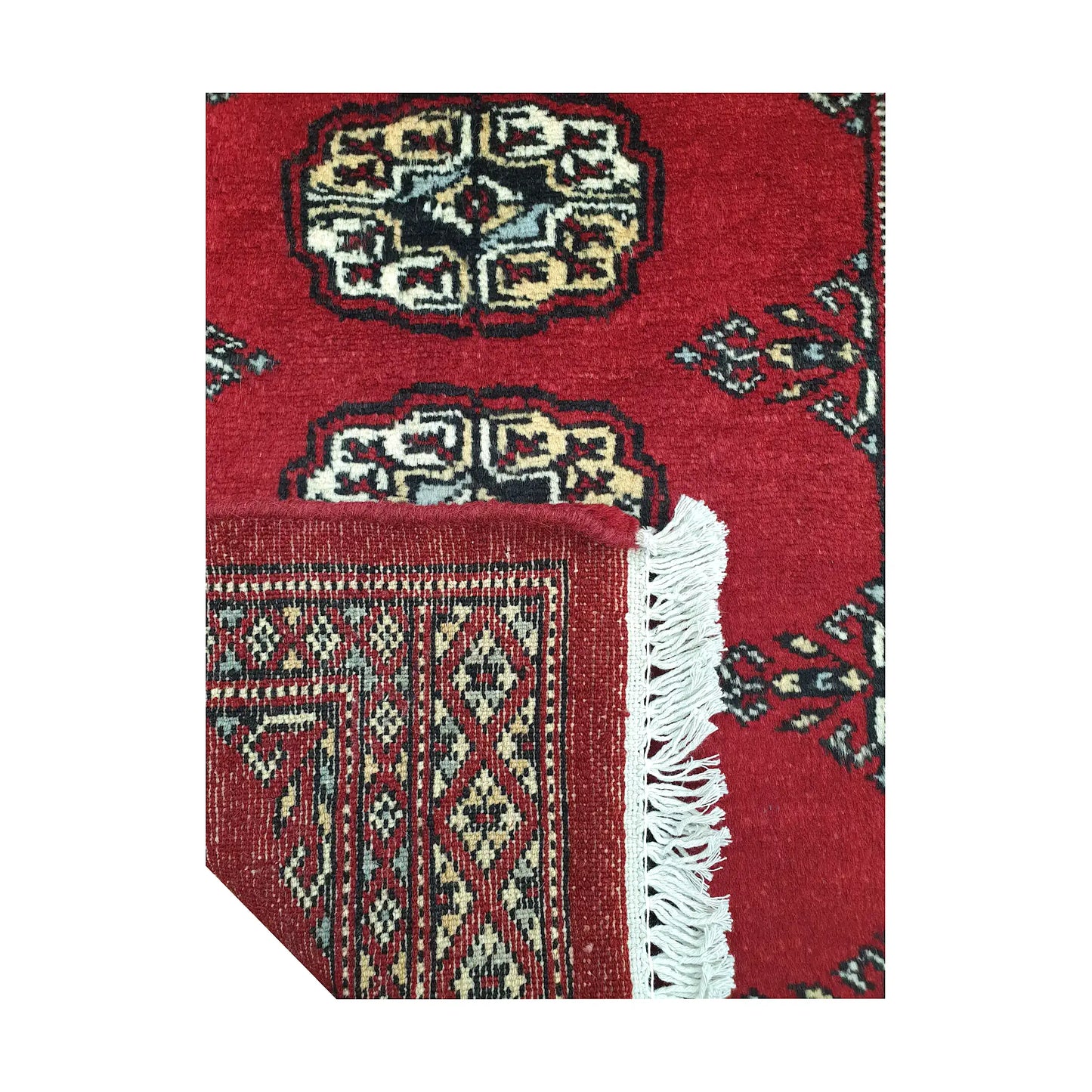 Folded corner detail of Afghan Bokhara wool rug showing the back of the rug, fringe and red front pattern