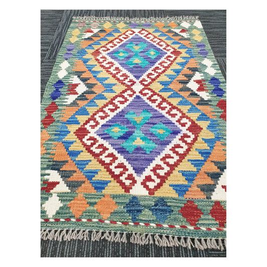Angled view of Afghan Chobi Kilim flatweave rug showing linked diamond geometric pattern, 90 x 60 cm