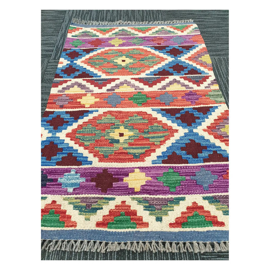 Angled view of Afghan Chobi Kilim flatweave rug showing geometric banded medallion pattern, 91 x 63 cm