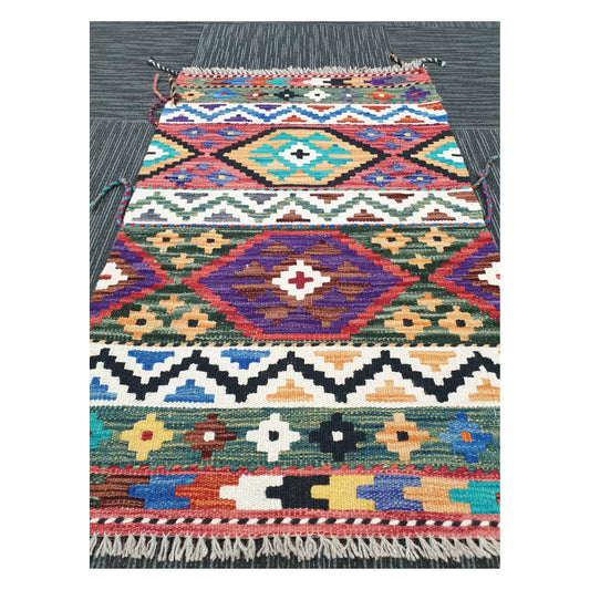 Angled view of Afghan Chobi Kilim flatweave rug showing multicolour banded diamond pattern, 96 x 60 cm