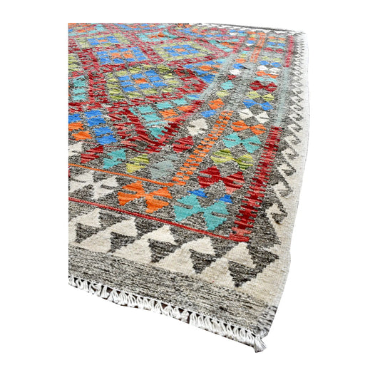 Angled border detail of Afghan Chobi Kilim rug showing colourful geometric motifs, grey triangles on ivory and pale fringe.