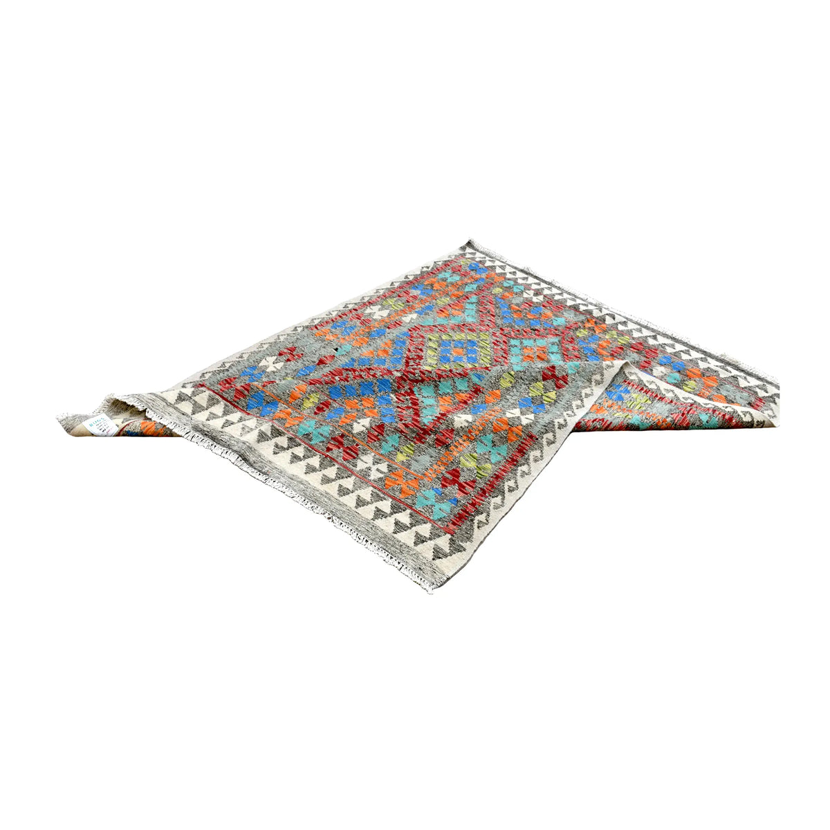 Folded view of Afghan Chobi Kilim rug showing its repeating diamond field, ivory geometric border and two corners turned back.