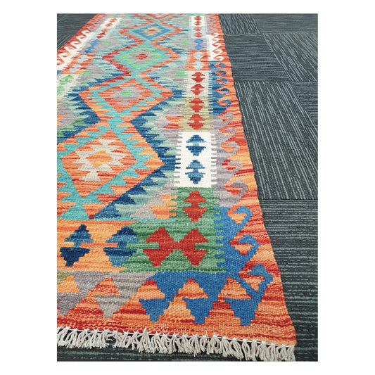 Angled view of Afghan Chobi Kilim runner showing linked medallion pattern and fringe, 207 x 65 cm
