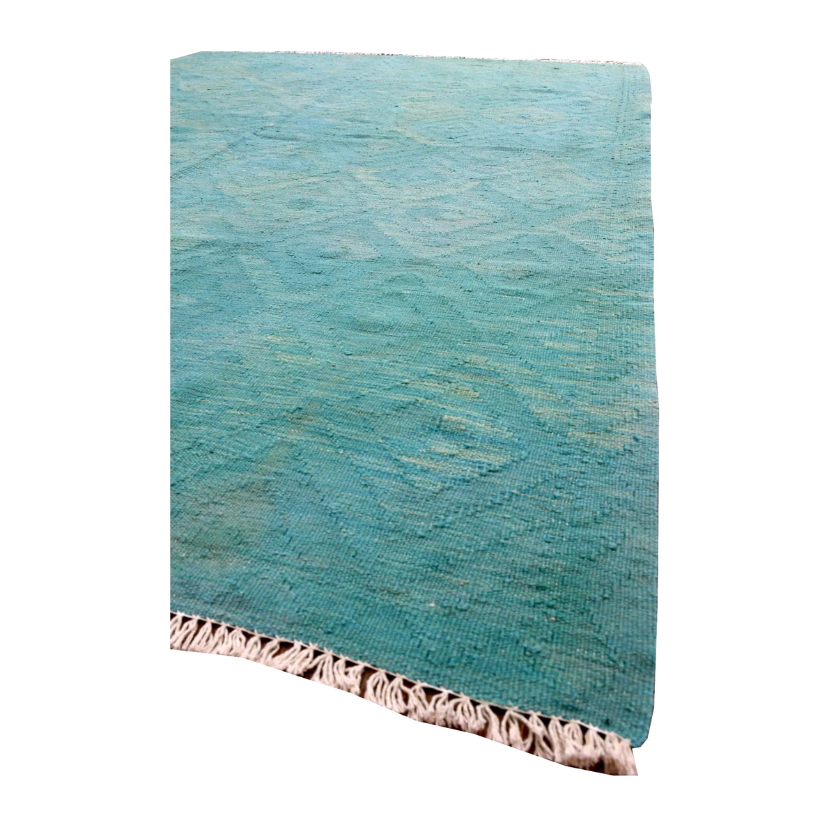 Angled detail of Afghan Chobi kilim showing its blue-green woven surface, faint geometric motifs and ivory fringe