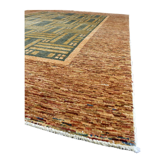 Angled view of Afghan Gabbeh rug showing its ochre geometric pattern, muted blue-green field, warm-brown border and white fringe
