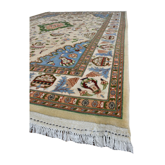 Angled view of Afghan Karghai rug showing its beige floral field, pale blue corner, layered border and white fringe
