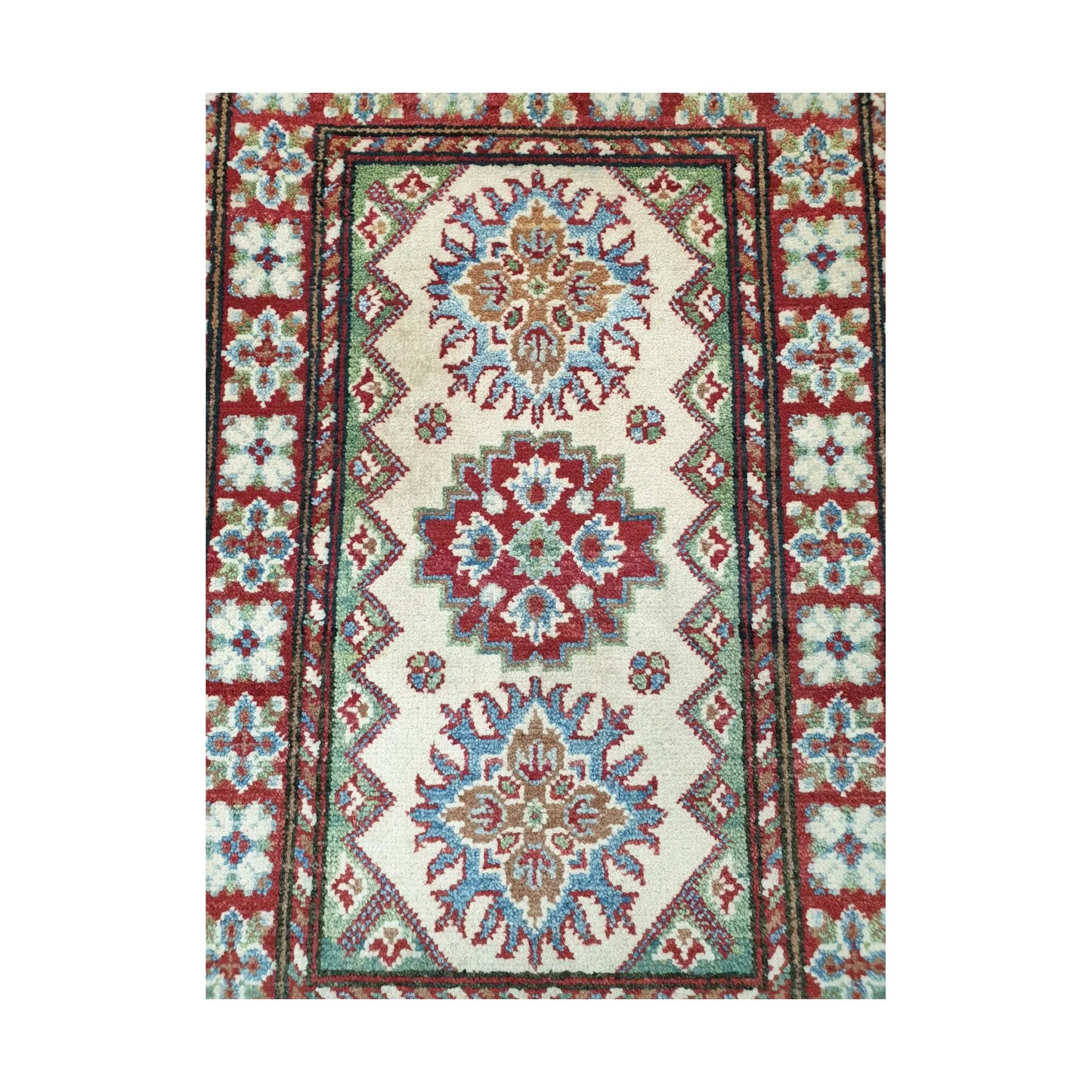 Detail of Afghan Kazak hand-knotted wool rug showing cream centre field, geometric medallions and framed border, 88 x 58 cm