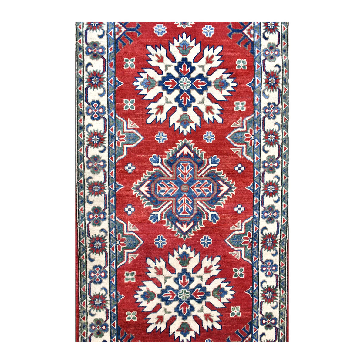Field detail of Afghan Kazak runner showing alternating ivory starburst and blue-red medallions across the red ground
