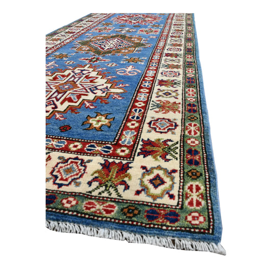 Angled end of Afghan Kazak runner showing layered ivory and red borders, blue field and short fringe