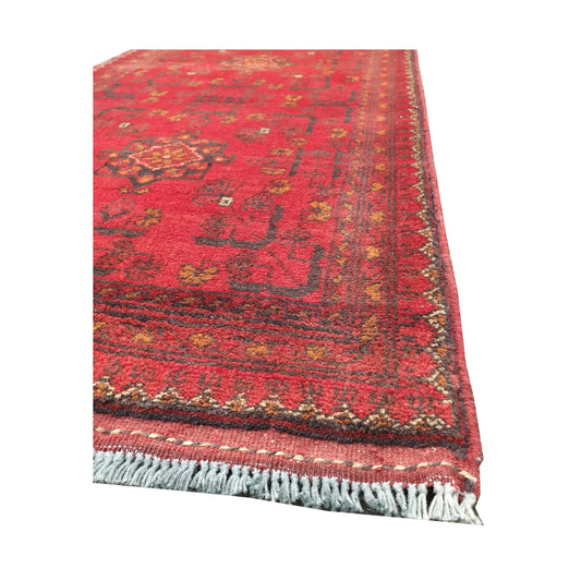 Angled corner and fringe view of Afghan Khal Mohammadi wool rug showing warm red field, dark border detail and light fringe