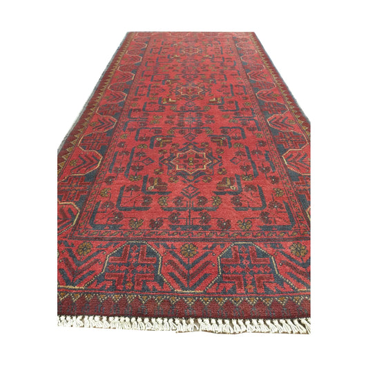 Angled full view of Afghan Khal Mohammadi wool runner rug showing red field, fringe and traditional geometric border