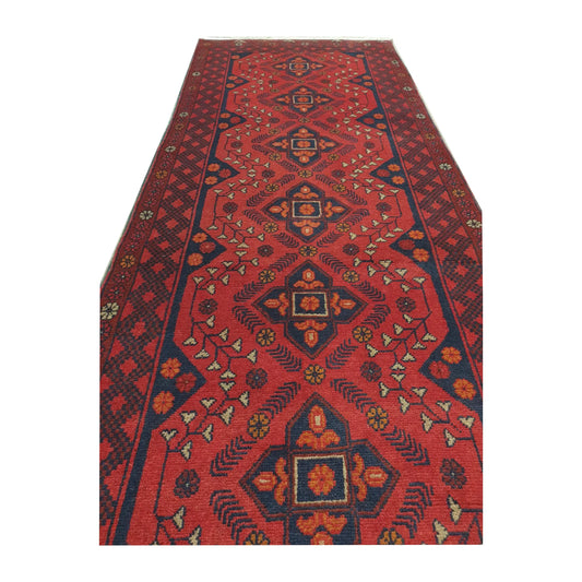 Angled full view of Afghan Khal Mohammadi wool runner rug showing red field, fringe and traditional geometric border