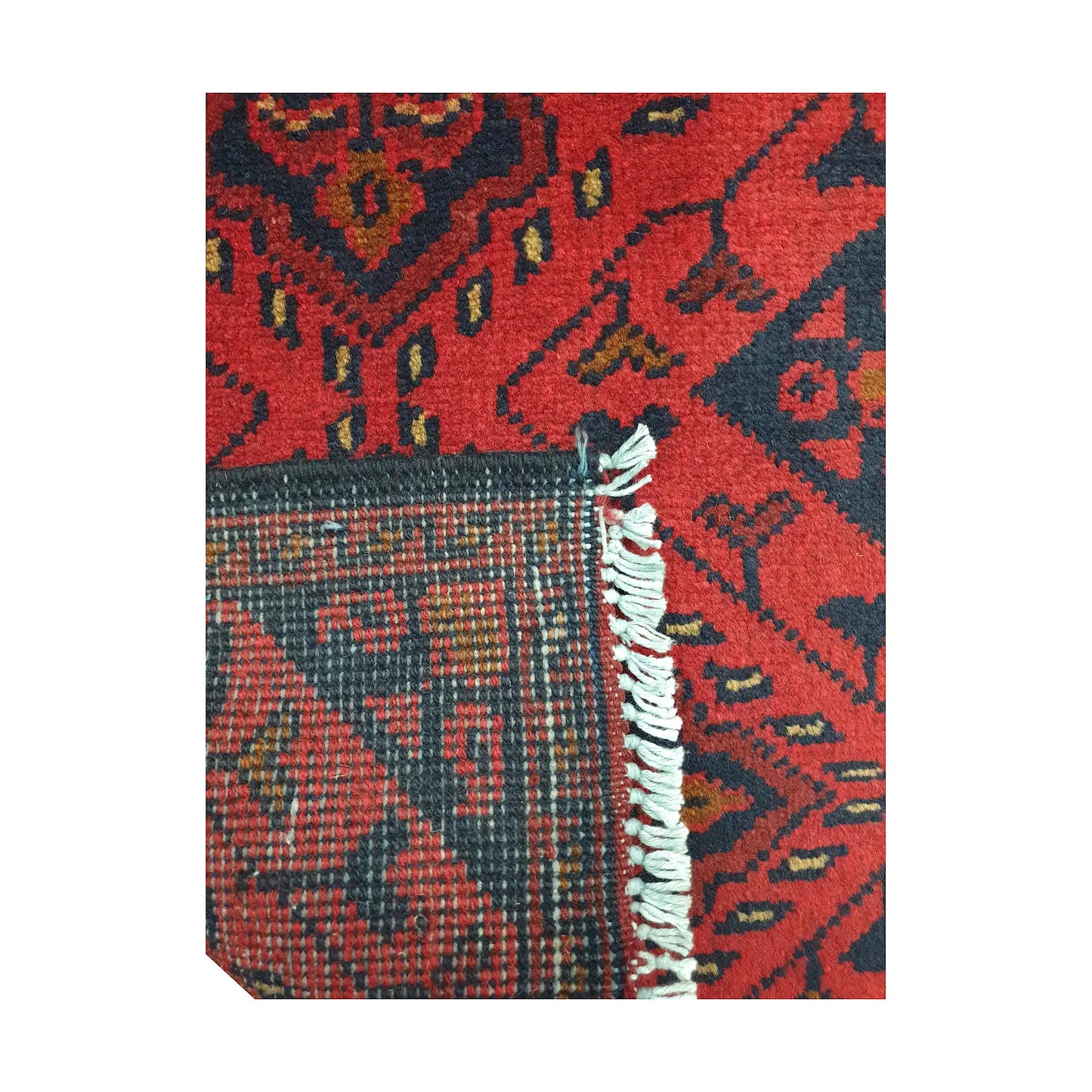 Folded corner detail of Afghan Khal Mohammadi wool rug showing the back, fringe and red front pattern