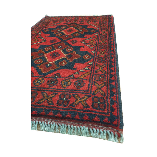 Angled detail of Afghan Khal Mohammadi wool rug showing layered geometric borders, fringe and red patterned field