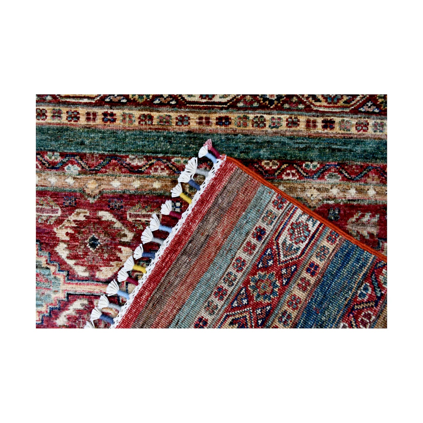 Folded corner detail of Afghan Khurjeen runner rug showing the back of the rug, fringe and front border pattern