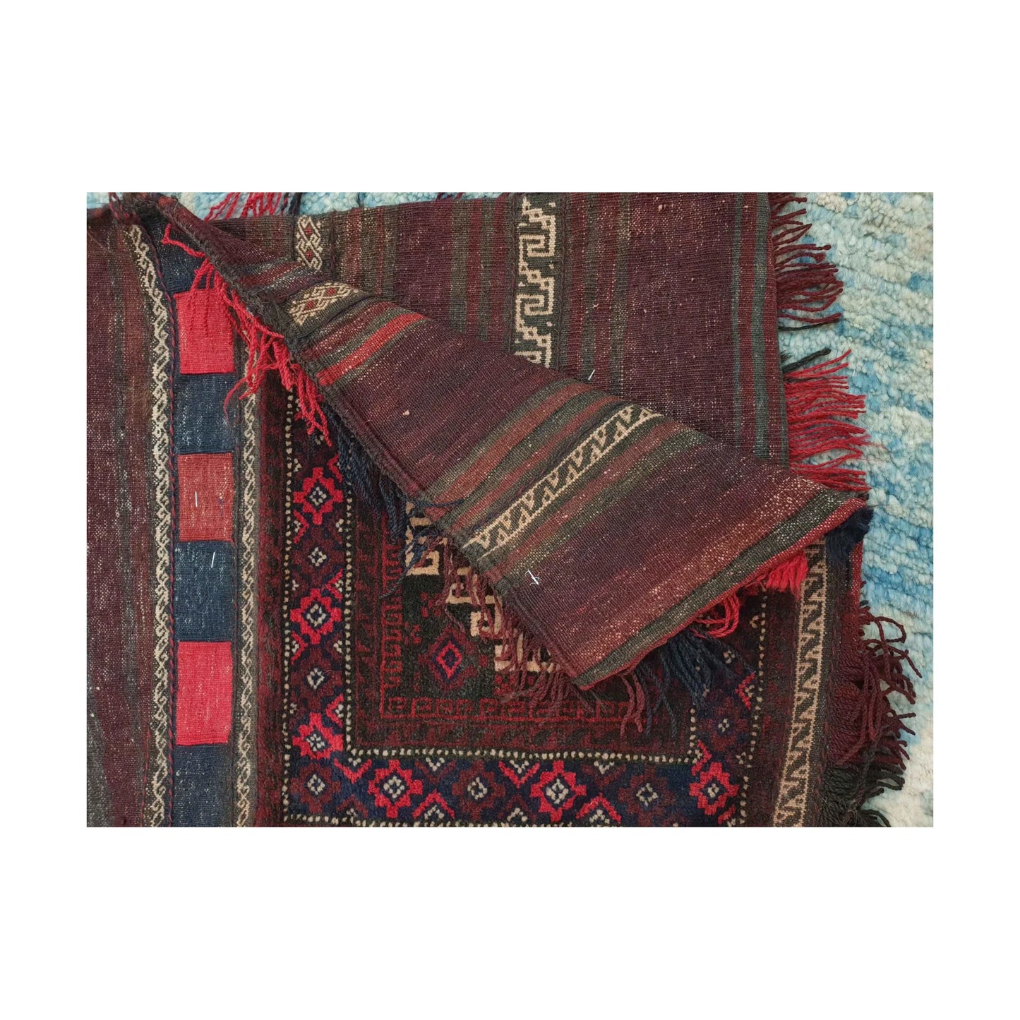 Folded reverse view of Afghan saddle bag showing burgundy striped flatweave, ivory geometric bands and fringe