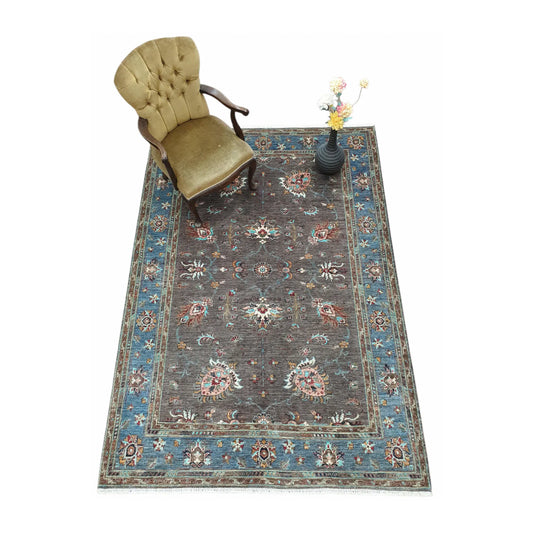 Afghan Sultani hand-knotted rug styled with chair and vase showing blue border and floral field