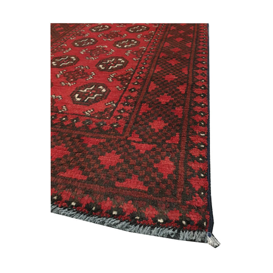 Angled field and border detail of Afghan Turkoman rug showing red wool pile, gul motifs and dark geometric edging