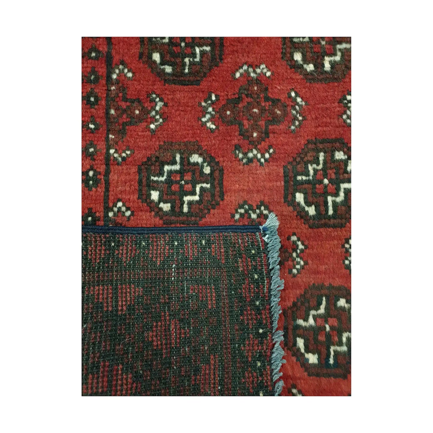 Folded corner detail of Afghan Turkoman rug showing the back of the rug and red gul pattern on the front
