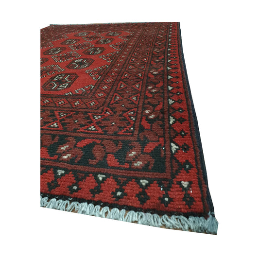 Angled border and fringe detail of Afghan Turkoman rug showing red wool pile, dark geometric edging and fringe