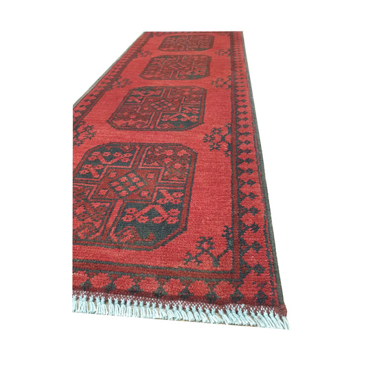 Angled border and fringe detail of Afghan Turkoman runner rug showing red wool pile, charcoal edging and tribal motifs