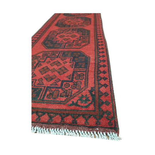 Angled border and fringe detail of Afghan Turkoman runner rug showing red wool pile, dark edging and tribal motifs
