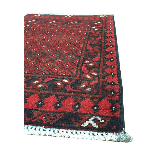 Angled border detail of Afghan Turkoman wool rug showing red field, layered geometric motifs and fringe