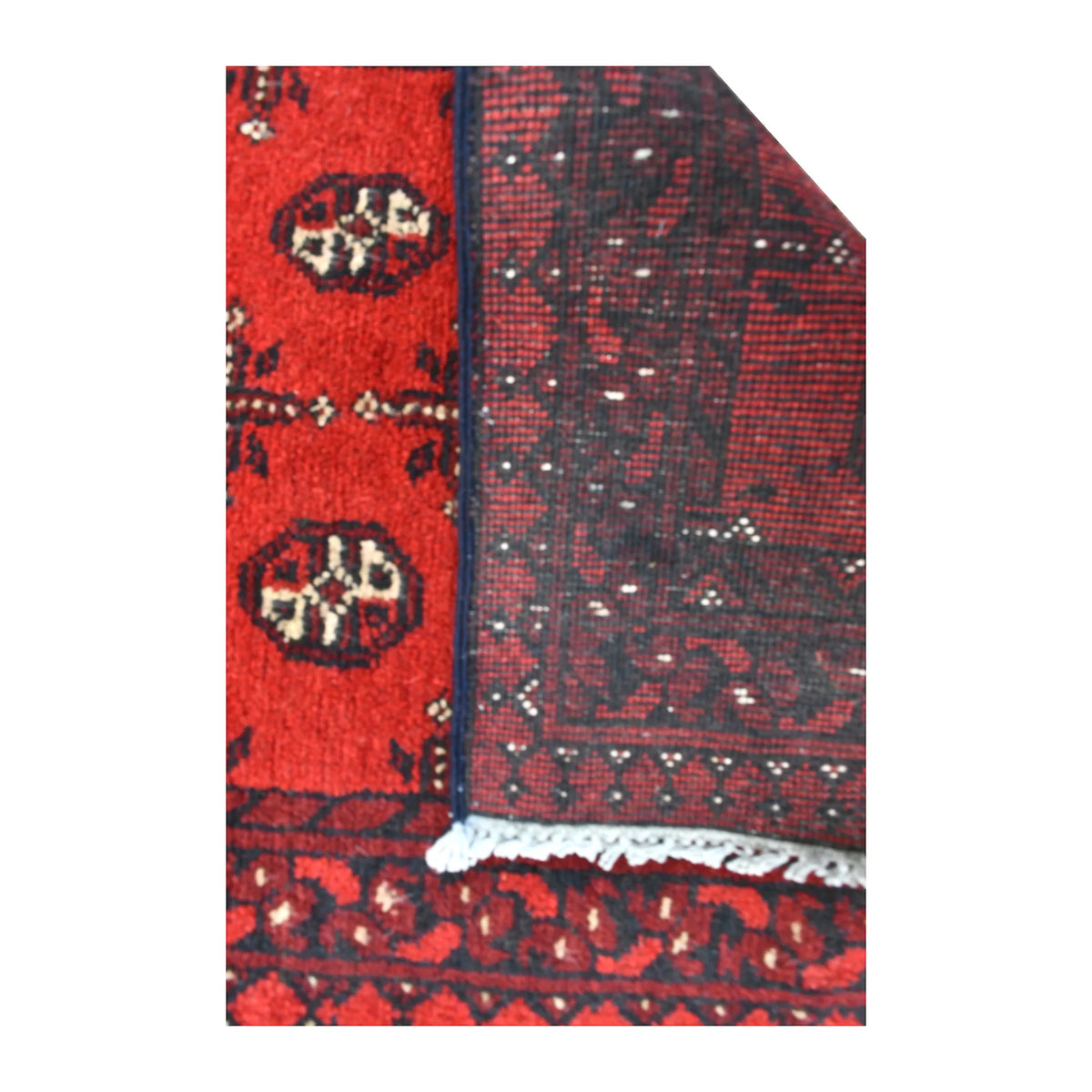 Folded-corner detail of Afghan Turkoman runner showing the reverse weave beside its red gul field and dark geometric border