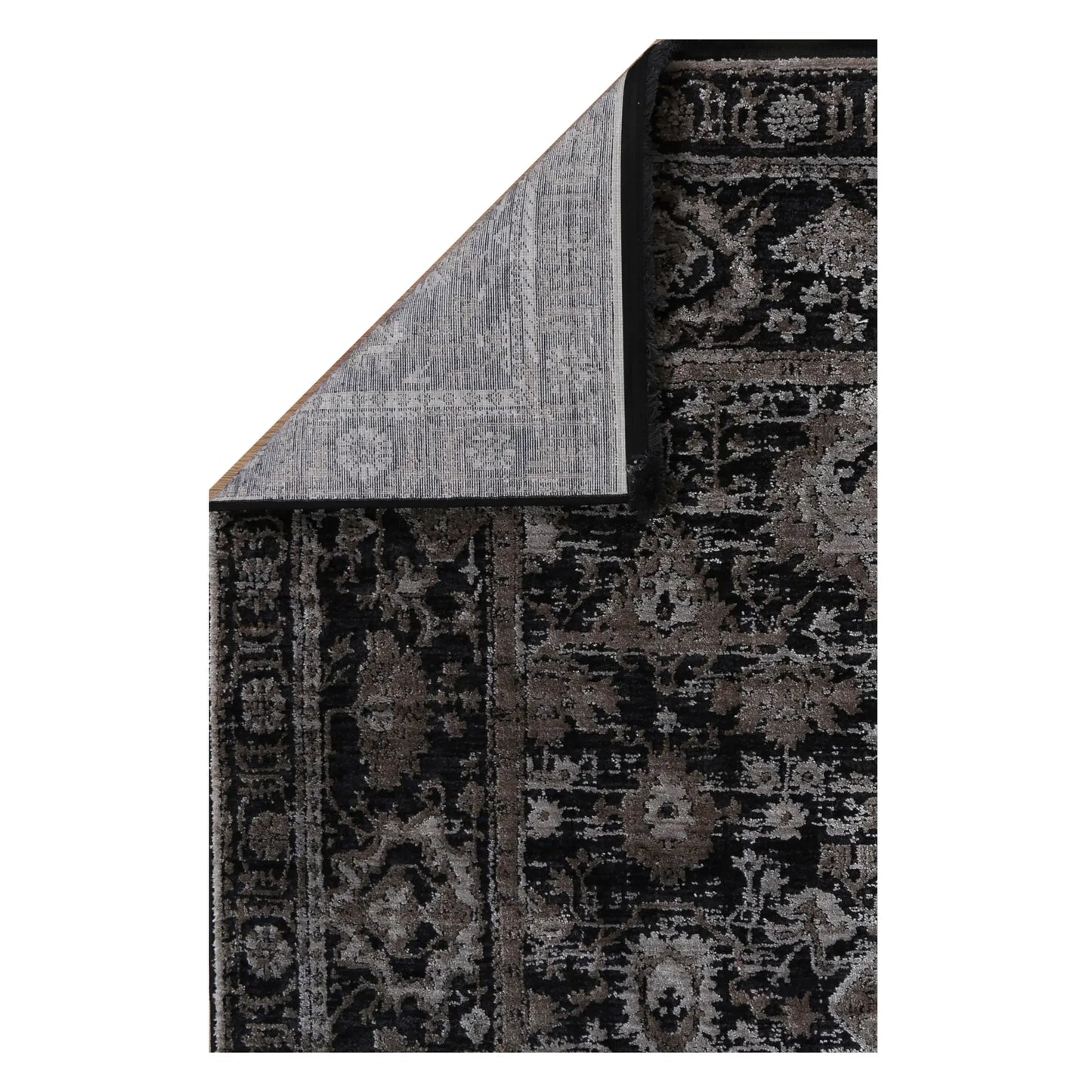 Folded corner of the Brooklyn 300 pewter rug showing the patterned pile, bound edge and woven backing