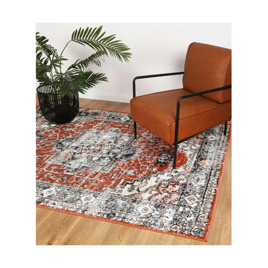Estate Terracotta medallion rug styled with a leather chair and plant, showing its terracotta, ivory and charcoal pattern