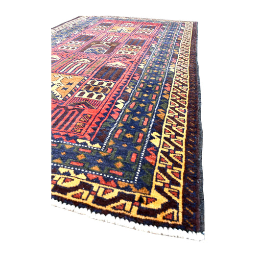 Angled view of Baluchi rug showing broad navy patterned borders, a gold hooked outer band and short cream fringe