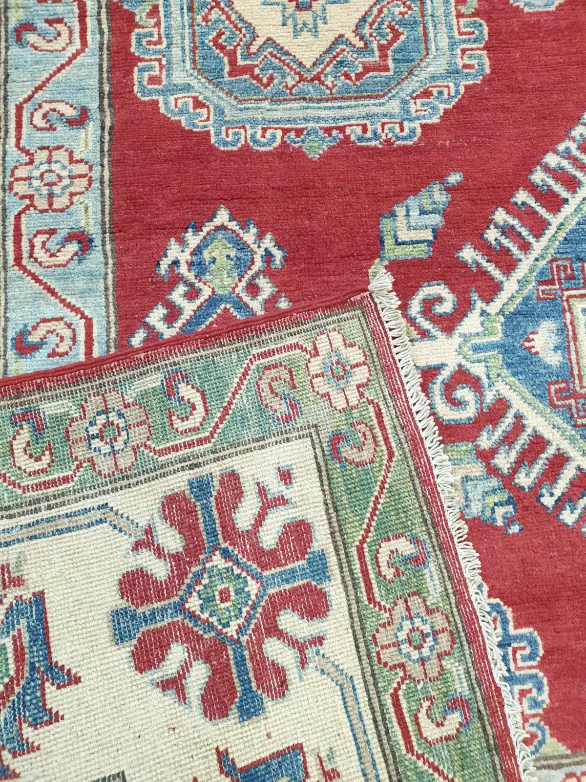 The reverse side of a hand-knotted Kazak rug, displaying the high knot density and authentic handmade construction of the wool base.
