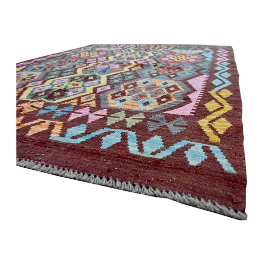 Angled edge detail of Handwoven Chobi Kilim rug showing fringe, flatwoven texture and burgundy border
