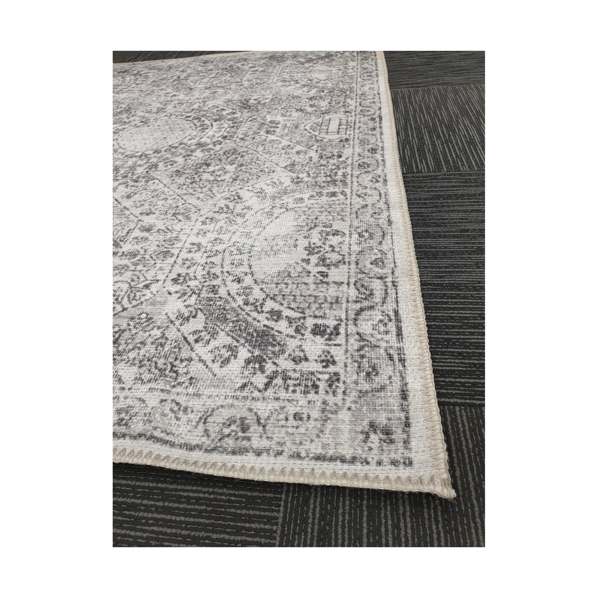Close-up of ivory grey cotton rug corner with floral border detail