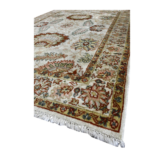 Angled view of Ziegler wool rug showing its ivory field, rust palmettes, muted green vines, floral borders and pale fringe