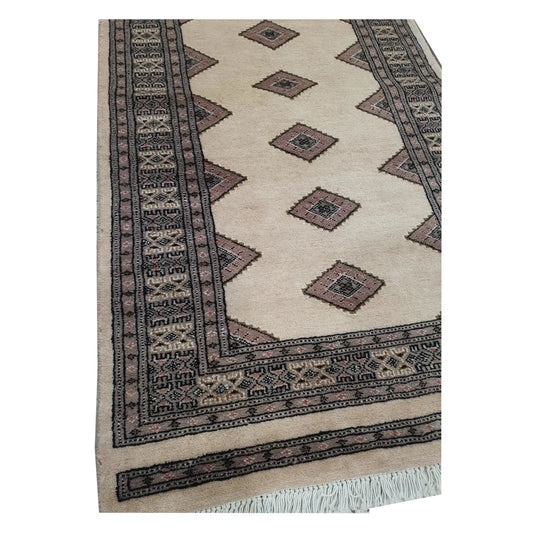 End detail of Jaldar Silk Touch runner rug showing beige field, angular diamond guls, black border and fringe