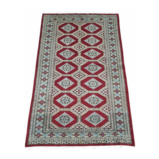 Angled full view of Jaldar wool rug showing the repeating angular guls, red field and layered geometric borders