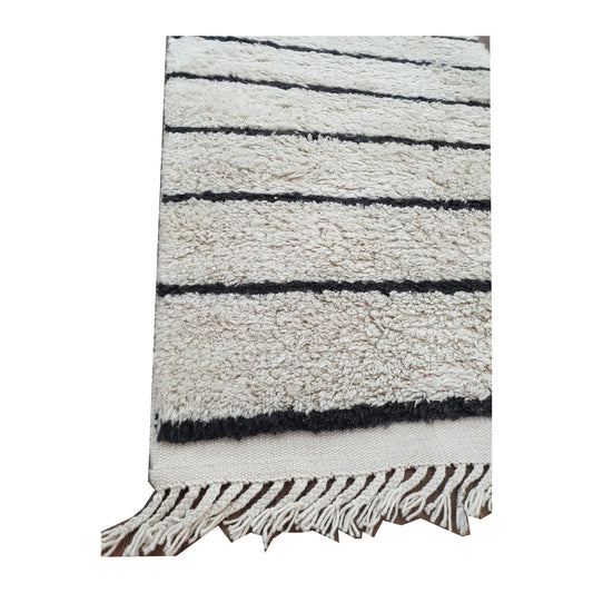 Close-up of Moroccan Design hand-knotted wool rug showing cream wool pile, black stripe detail and fringe edge, 165 x 90 cm