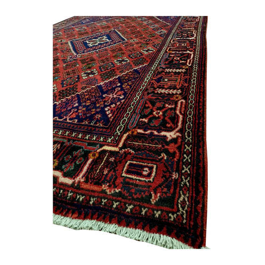 Angled close view of the Persian Meimeh rug showing its compartmental border, wool pile and cream fringe