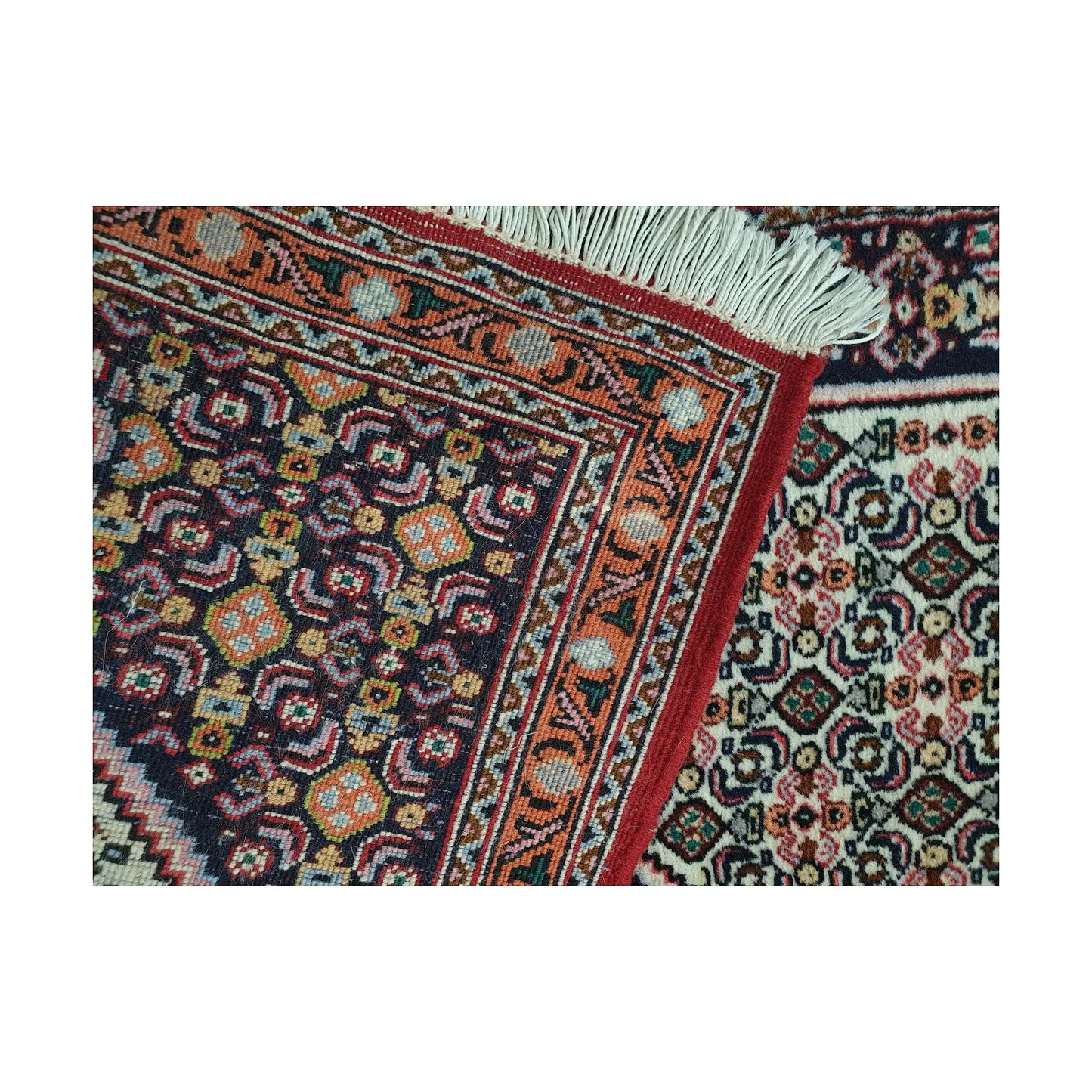 Folded corner detail of Persian Senneh runner showing the back of the rug, fringe and fine front pattern