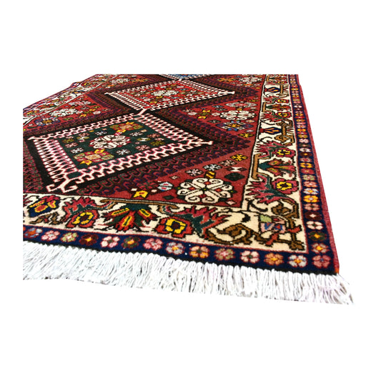 Angled corner detail of Persian Shiraz runner showing the cream-ground floral border, patterned pile and ivory fringe