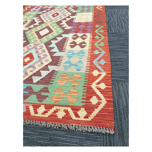 Angled detail of Afghan Chobi Kilim showing fringe, terracotta border, and handwoven geometric pattern, 143 x 107 cm