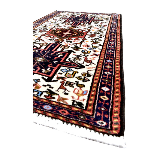Angled view of vintage Afshar rug showing navy medallions, small animal and duck motifs, narrow patterned borders and white fringe