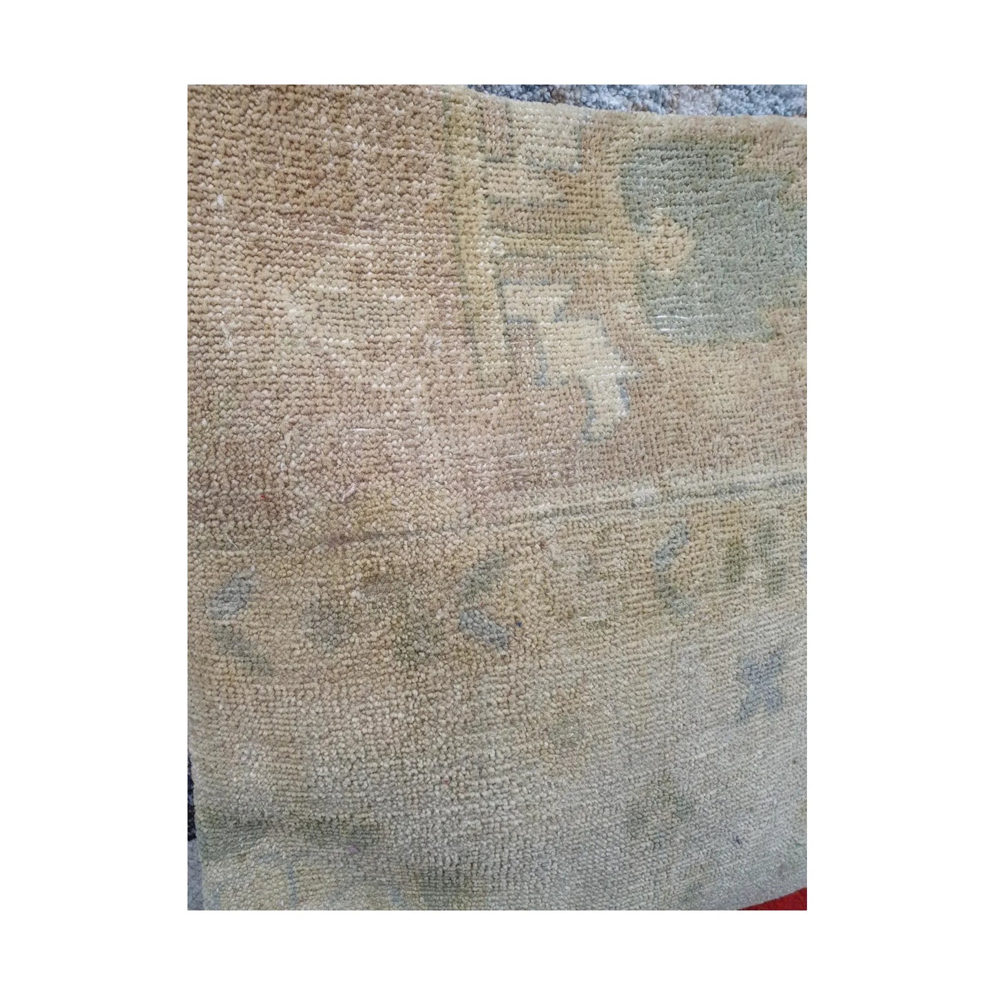 Detailed view of softly faded beige wool pile with geometric and linear Persian pattern traces