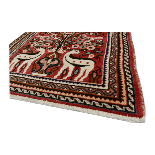 Angled corner and fringe view of vintage Persian Hamadan wool rug showing red field, patterned border and light fringe