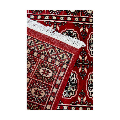 Folded corner detail of Afghan Bokhara runner rug showing the back of the rug, fringe and red front border