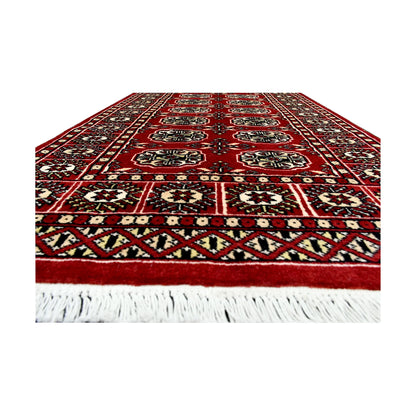 Fringe end detail of Afghan Bokhara runner rug showing repeated gul medallions, red field and geometric border