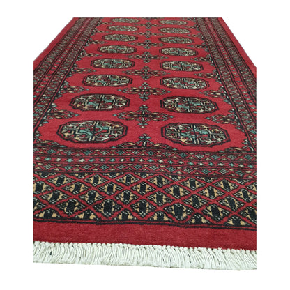 End field and fringe detail of Afghan Bokhara runner rug with red gul medallions and geometric end border